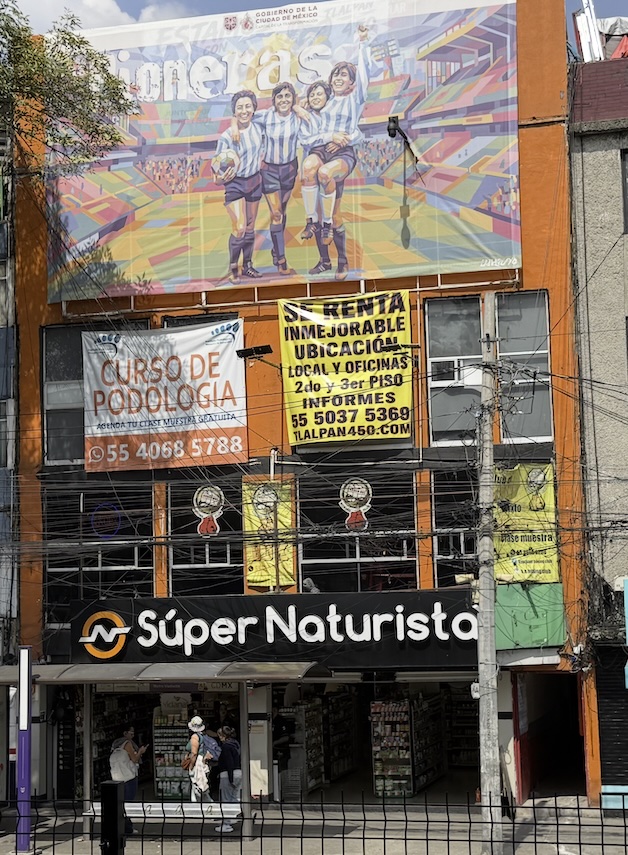 Fachada de Tlalpan 450 con espectacular en la parte alta, tienda Súper Naturista en planta baja y parada del Metro Viaducto a un costado